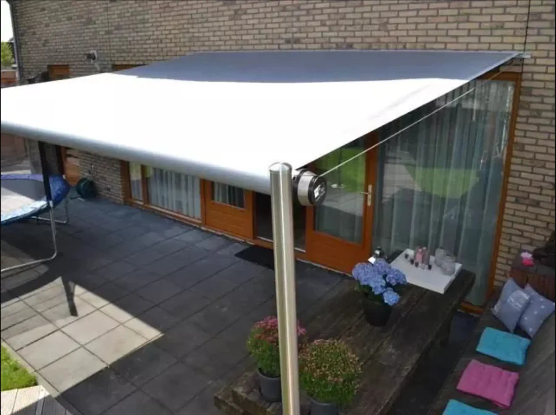 Freistehende Markise über einer Terrasse mit Sitzbereich an einem Wohnhaus